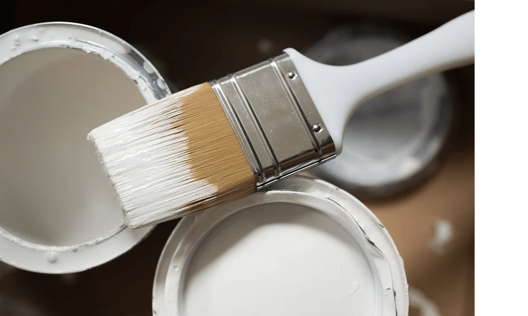 paintbrush with a white handle, paintbrush dipped in white paint, two pints of white paint, the cover of paint the tub on the floor