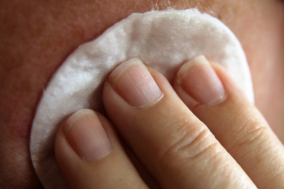 three fingers, cotton pad, a part of a human’s face
