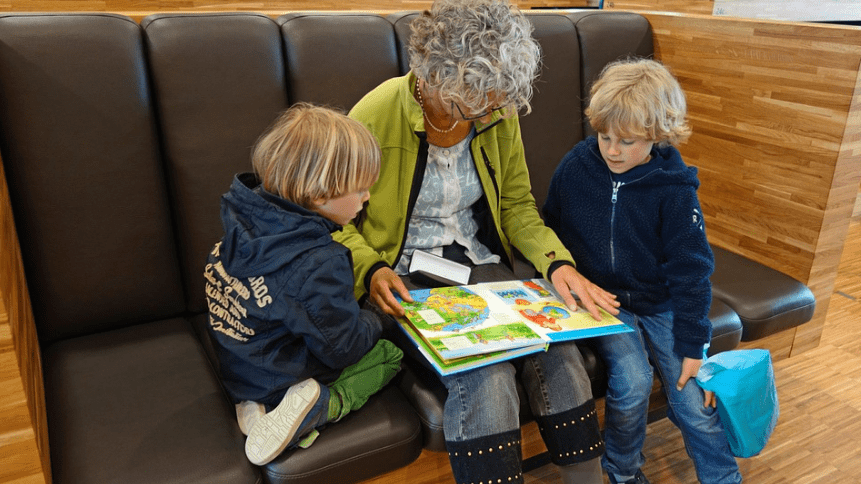 a grandmother holding a story book, with her grand sons