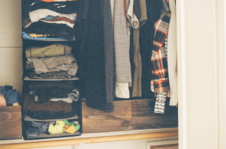 hanging clothes, wooden drawers, stackable closet shelves with clothes