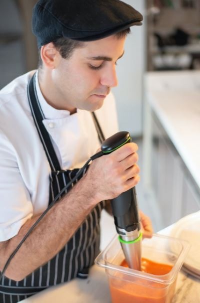 a chef using an immersion blender to puree and sauce