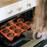 a person pulling a muffin pan out of the oven