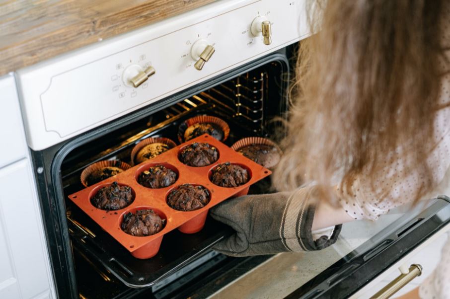 a person pulling a muffin pan out of the oven